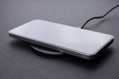 Koyu arkaplanda kablosuz şarj cihazında cep telefonu var. Akıllı telefonlar güç kaynağına bağlı. düşük pil seviyesi sorunları.