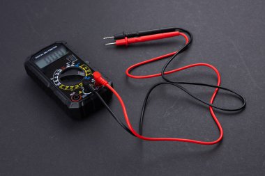 Sondaları olan ve koyu arkaplanda izole edilmiş dijital çokölçer. Elektrikli alet. Siyah dijital çokölçer, karanlık arka planda sondalar, çokölçer elektronik bir ölçüm aletidir.