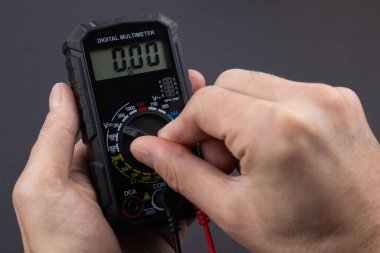 Erkek tamircinin evde dijital çoklu sayaçla buzdolabını kontrol ederken çekilmiş görüntüsü.