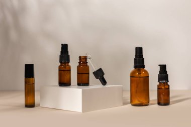 Bej arka planda bir podyumda pipeti olan kahverengi cam şişe, doğal kozmetik konsept..