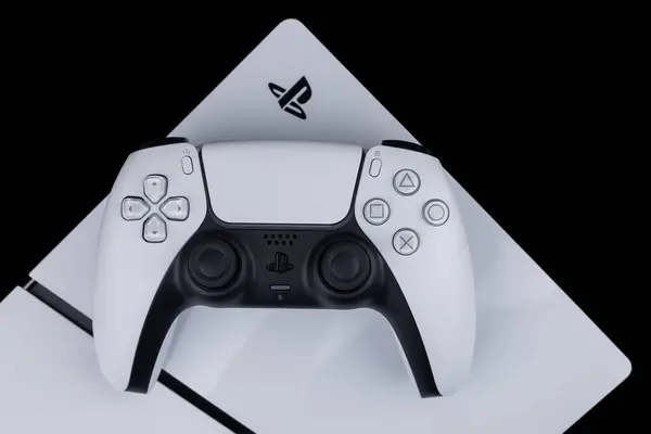 Dnipro Ukrayna - 29 Aralık 2024: Karanlık bir masa üzerinde beyaz bir Sony Playstation 5 denetleyici ve PlayStation 5 konsolu.