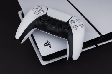 Dnipro Ukrayna - 29 Aralık 2024: Karanlık bir masa üzerinde beyaz bir Sony Playstation 5 denetleyici ve PlayStation 5 konsolu.