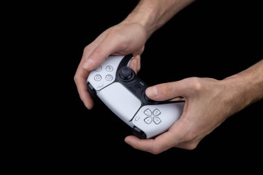 Dnipro Ukrayna - dec 29, 2024: Dualsense kontrol cihazını kullanarak bilgisayar oyunları oynamak. Playstation 5 denetleyicisi tutan adam.