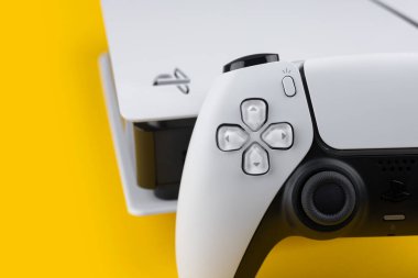 Dnipro Ukrayna - 29 Aralık 2024: Sarı bir masa üzerinde beyaz Sony Playstation 5 denetleyici ve PlayStation 5 konsolu.