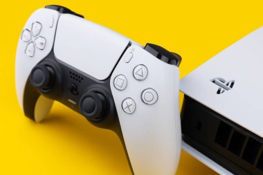 Dnipro Ukrayna - 29 Aralık 2024: Sarı bir masa üzerinde beyaz Sony Playstation 5 denetleyici ve PlayStation 5 konsolu.