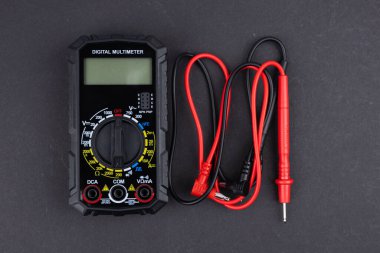 Sondaları olan ve koyu arkaplanda izole edilmiş dijital çokölçer. Elektrikli alet. Siyah dijital çokölçer, karanlık arka planda sondalar, çokölçer elektronik bir ölçüm aletidir.
