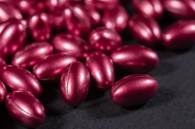 koyu arkaplanda vitaminlerin kırmızı yumuşak kapsülleri.