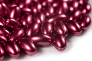 beyaz arkaplanda vitaminlerin kırmızı yumuşak kapsülleri.