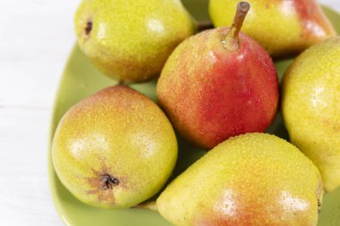 Yeşil tabakta su damlalarıyla olgun armutlar.