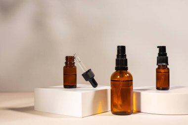 Kehribar cam kozmetik şişeleri krem ya da sıvı ile bej arka planda beyaz beton podyumda cilt bakımı için. Doğal cilt bakımı kavramı