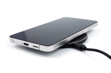 Beyaz arka planda kablosuz şarj cihazında cep telefonu var. akıllı telefonlar güç kaynağına bağlandı.