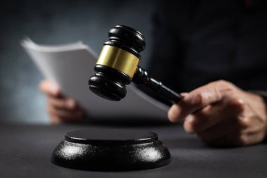 Mahkemede hüküm verildiğini bildiren kağıt belgelerle hakim. Yargıç sanığı suçlu buldu, kararı verdi ve dava kapandı. El ele tutuşup yakın planda ses bloğuna çarpacağız.