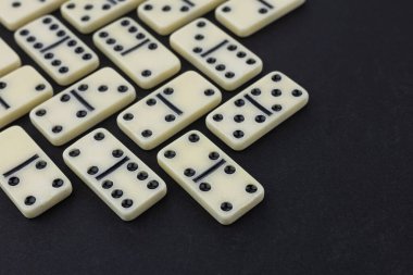 Satranç taşlarının ve dominoların düz kompozisyonu karanlık masanın üzerinde yatıyordu..