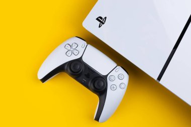 Dnipro Ukrayna - 29 Aralık 2024: Sarı bir masa üzerinde beyaz Sony Playstation 5 denetleyici ve PlayStation 5 konsolu.