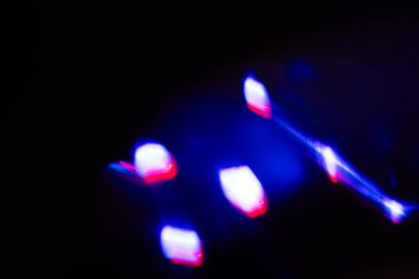 Bulanık neon ışık. Mercek alevi kaplaması. Bokeh floresan flaş parıltısı. Koyu siyah soyut arkaplanda odaklanmış mavi mor renk lekeleri.