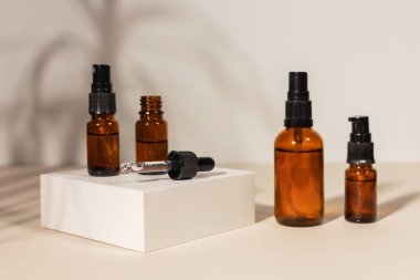 Bej arka planda bir podyumda pipeti olan kahverengi cam şişe, doğal kozmetik konsept..