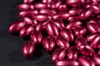 koyu arkaplanda vitaminlerin kırmızı yumuşak kapsülleri.