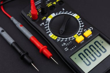 Sondaları olan ve koyu arkaplanda izole edilmiş dijital çokölçer. Elektrikli alet. Siyah dijital çokölçer, karanlık arka planda sondalar, çokölçer elektronik bir ölçüm aletidir.