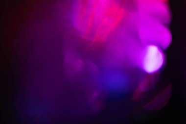 Neon bulanıklığı parlıyor. Renk ışığı örtüsü. Disko aydınlatması. Odaklanmamış mavi mor ötesi ışıltı koyu soyut boş arkaplan üzerindeki yumuşak doku.
