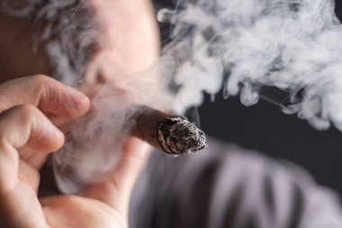 Küba purosu içen ve elinde puro tutan bir adam.,