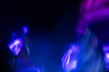 Bulanık neon ışık. Mercek alevi kaplaması. Bokeh floresan flaş parıltısı. Koyu siyah soyut arkaplanda odaklanmış mavi mor renk lekeleri.