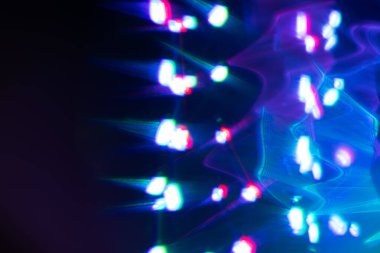 Siyah arkaplanda renkli ışık sızıntısı, uzun mercekte optik mercek parlaması olan soyut tasarım.