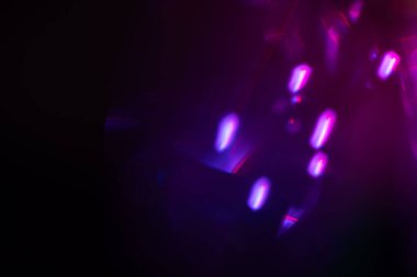Bulanık neon ışık. Mercek alevi kaplaması. Bokeh floresan flaş parıltısı. Koyu siyah soyut arkaplanda odaklanmış mavi mor renk lekeleri.