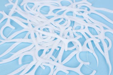 Mavi arka planda diş ipi izleri var. Yumuşak diş ipi kazmaları. Diş kıracağı. Diş ipli plastik beyaz bir kürdan..