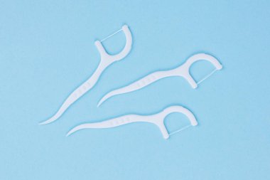 Mavi arka planda diş ipiyle plastik beyaz diş kürdanı.