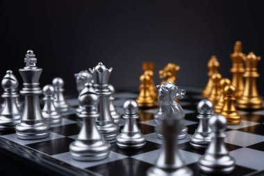 Tahta satranç tahtasına altın ve gümüş satranç figürleri yerleştirildi. İş hayatında entelektüel düello ve taktiksel savaş. Strateji planlaması, liderlik ve takım çalışması kavramı.