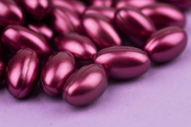 Pembe zemin üzerinde vitamin kapsülleri.