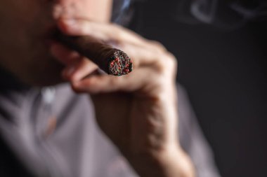 Küba purosu içen ve elinde puro tutan bir adam.,