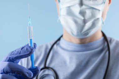 Maske takan ve eldiven takan bir doktor aşıyı enjekte etmeden önce ölçer..