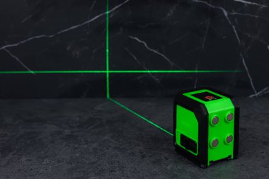 Bloklardan bir duvar inşa ederken lazer seviyesi. İnşaat alanlarındaki hatları ve seviyeleri belirlemek için lazer seviyesi tamamlanmamış beton bloklardan yapılmış bir duvarın üzerinde duruyor..