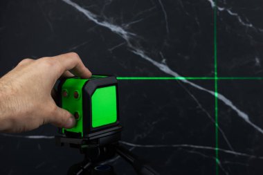 Bloklardan bir duvar inşa ederken lazer seviyesi. İnşaat alanlarındaki hatları ve seviyeleri belirlemek için lazer seviyesi tamamlanmamış beton bloklardan yapılmış bir duvarın üzerinde duruyor..