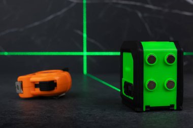 Yapı araçları, yeşil lazer seviye ölçer ve koyu arkaplanda mezura.