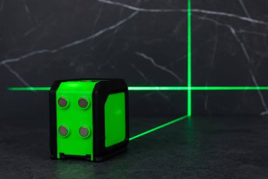 Bloklardan bir duvar inşa ederken lazer seviyesi. İnşaat alanlarındaki hatları ve seviyeleri belirlemek için lazer seviyesi tamamlanmamış beton bloklardan yapılmış bir duvarın üzerinde duruyor..