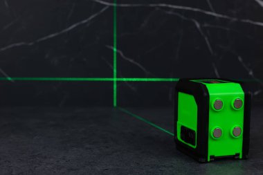 Bloklardan bir duvar inşa ederken lazer seviyesi. İnşaat alanlarındaki hatları ve seviyeleri belirlemek için lazer seviyesi tamamlanmamış beton bloklardan yapılmış bir duvarın üzerinde duruyor..