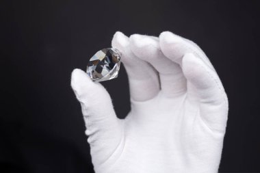 Mücevher aletleriyle cilalanmış elmasların değerlendirilmesinde elmas uzmanının ellerinin yakınlaştırılması.