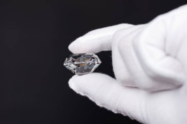 Mücevher aletleriyle cilalanmış elmasların değerlendirilmesinde elmas uzmanının ellerinin yakınlaştırılması.