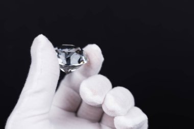 Elmas uzmanı beyaz eldivenli elmasların yakınlaştırılması. Mücevher aletleri kullanılarak parlaklaştırılmış elmasların değerlendirilmesi..