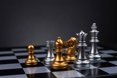 Tahta satranç tahtasına altın ve gümüş satranç figürleri yerleştirildi. İş hayatında entelektüel düello ve taktiksel savaş. Strateji planlaması, liderlik ve takım çalışması kavramı.