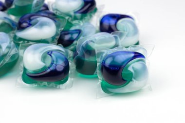 Çamaşır makinesi için çamaşır deterjanı kapsülleri beyaz arka planda.