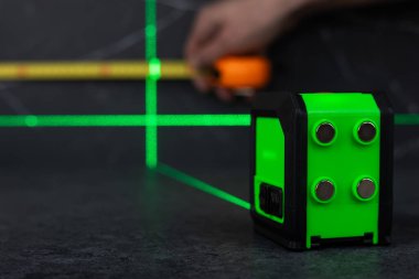 Masa üstü genişliğini mezura ve lazerle ölçen bir işçinin elleri.