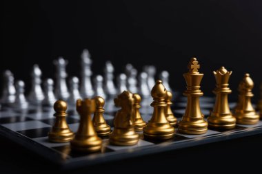 Altın ve gümüş satranç, Kral kraliçe at gemisi ve ticari savaş ve rekabet stratejisi konsepti için karanlık arka planda piyon içerir.