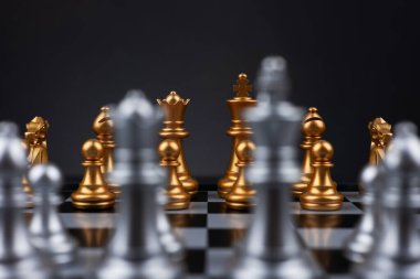 Altın ve gümüş satranç, Kral kraliçe at gemisi ve ticari savaş ve rekabet stratejisi konsepti için karanlık arka planda piyon içerir.