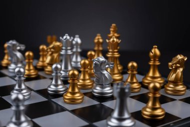 Altın ve gümüş satranç, Kral kraliçe at gemisi ve ticari savaş ve rekabet stratejisi konsepti için karanlık arka planda piyon içerir.