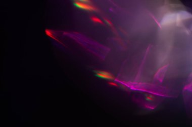 Siyah arkaplanda renkli ışık sızıntısı, uzun mercekte optik mercek parlaması olan soyut tasarım.