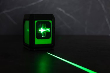 Bloklardan bir duvar inşa ederken lazer seviyesi. İnşaat alanlarındaki hatları ve seviyeleri belirlemek için lazer seviyesi tamamlanmamış beton bloklardan yapılmış bir duvarın üzerinde duruyor..