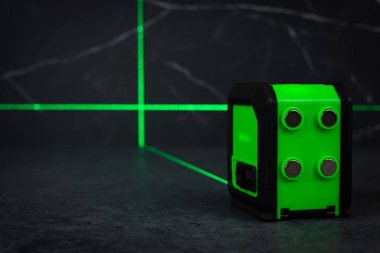 Bloklardan bir duvar inşa ederken lazer seviyesi. İnşaat alanlarındaki hatları ve seviyeleri belirlemek için lazer seviyesi tamamlanmamış beton bloklardan yapılmış bir duvarın üzerinde duruyor..